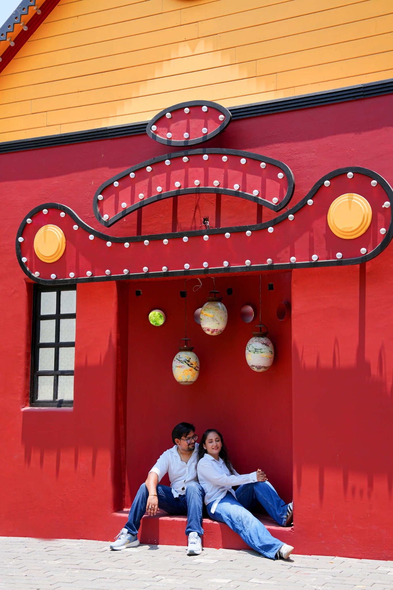 Arpit and Shivangi in front of a red architectural wall